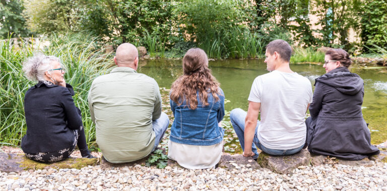 Fünf Personen die an einem Fluss sitzen