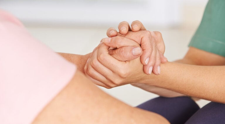 Krankenschwester hält Hände einer Seniorin