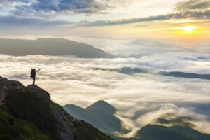 Mann Weit oben auf dem Bergen über dem Nebel im Tal