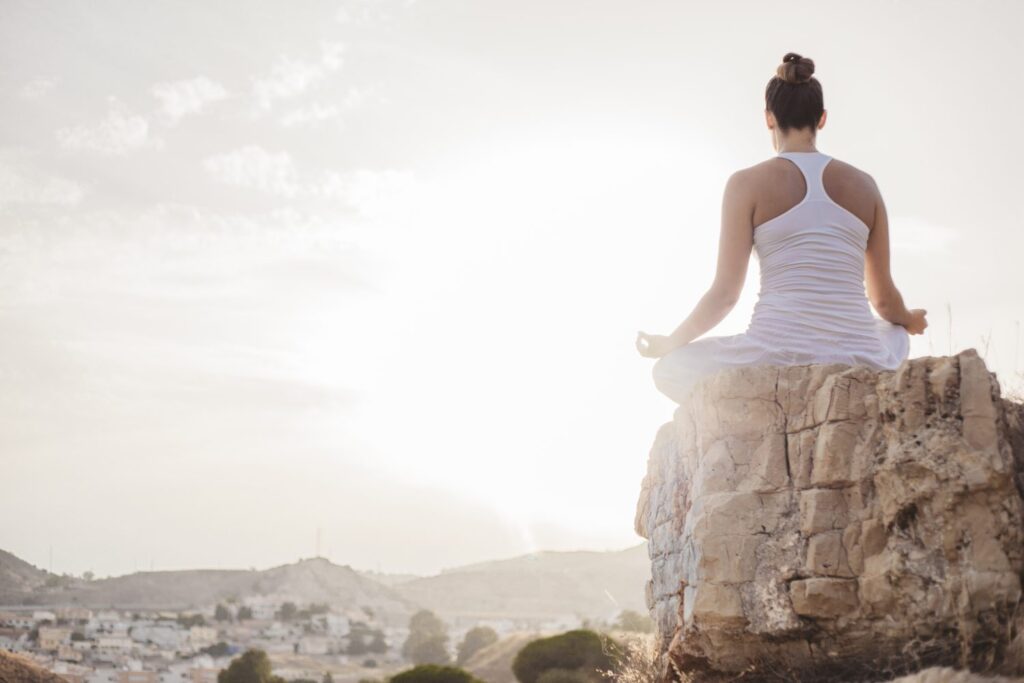 Meditation auf Fels mit Ausblick auf ein Dorf