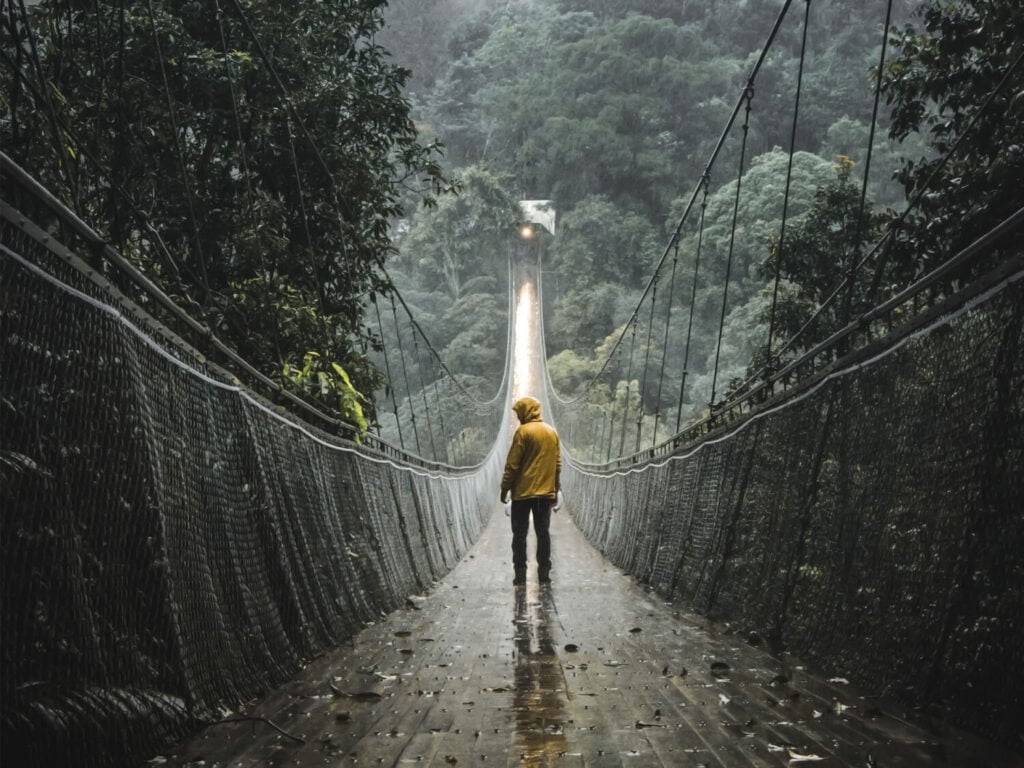 Mann geht im Regen über große Hängebrücke