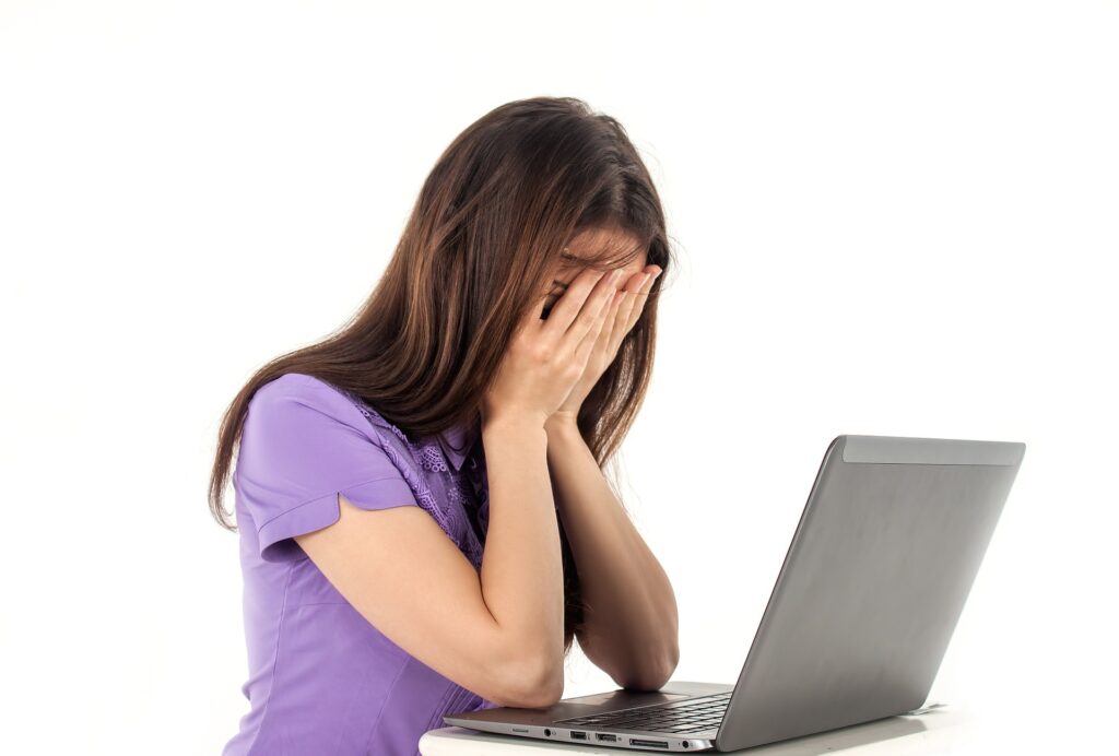 Junge Frau verzweifelt vor dem Laptop