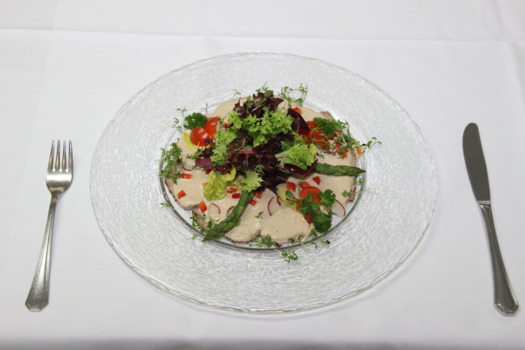Salat auf Glasteller daneben Besteck