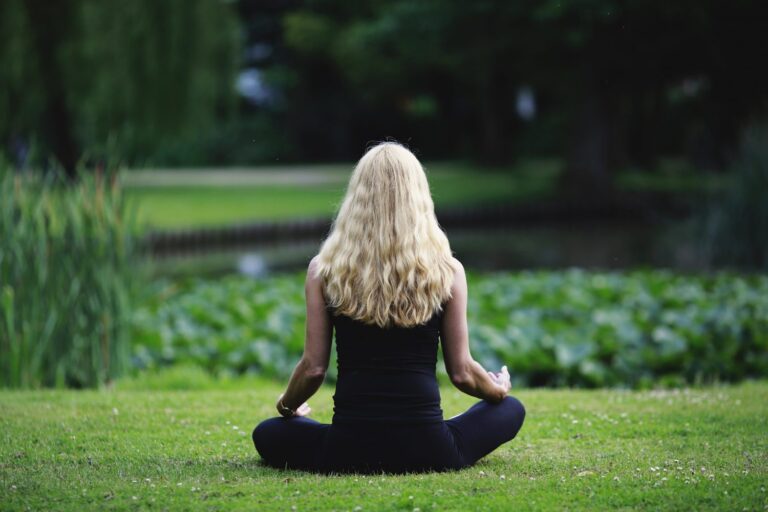 Frau in komplett schwarz meditiert im Park