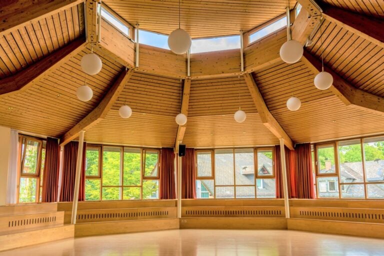 Großer Saal mit Holzdecke und rundum Fenstern