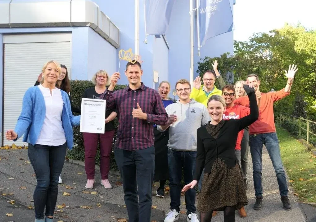 EIne Gruppe von Menschen hält eine Urkunde und freut sich.