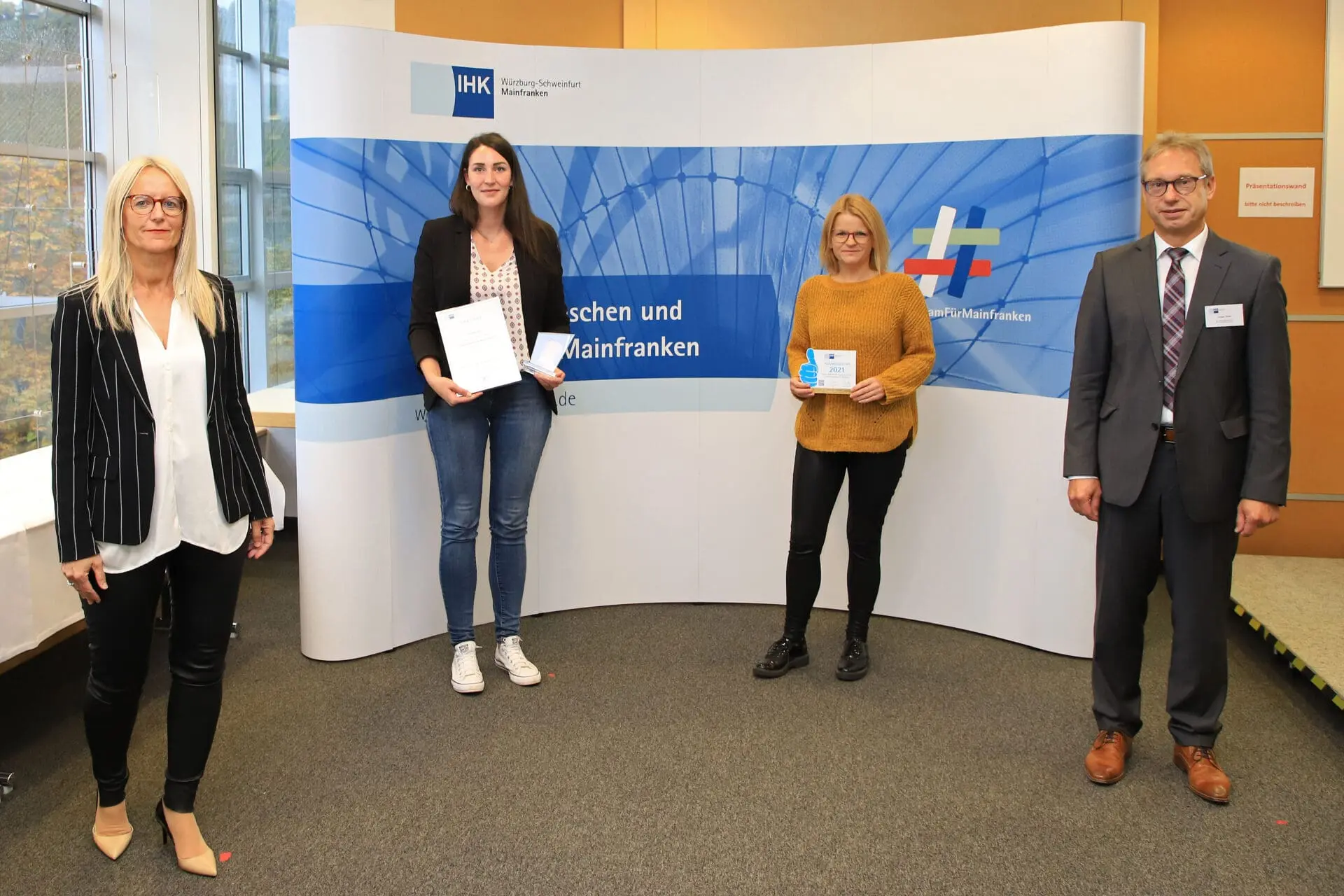Vier Personen stehen vor einer Wand mit IHK-Logo.