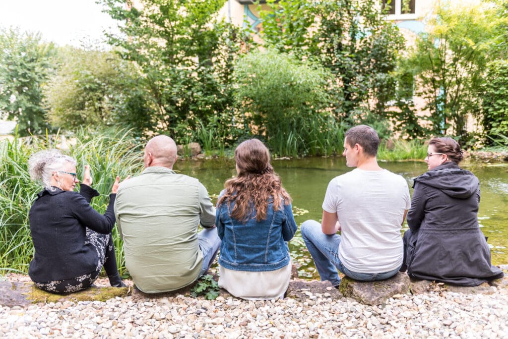 Zwei Männer und drei Frauen die am Fluss sitzen