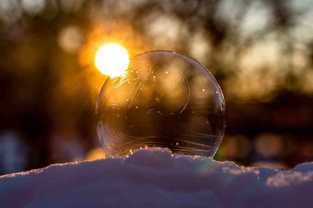 Header: Winterblues- Gefrorene Seifenblase, die den Sonnenuntergang spiegelt