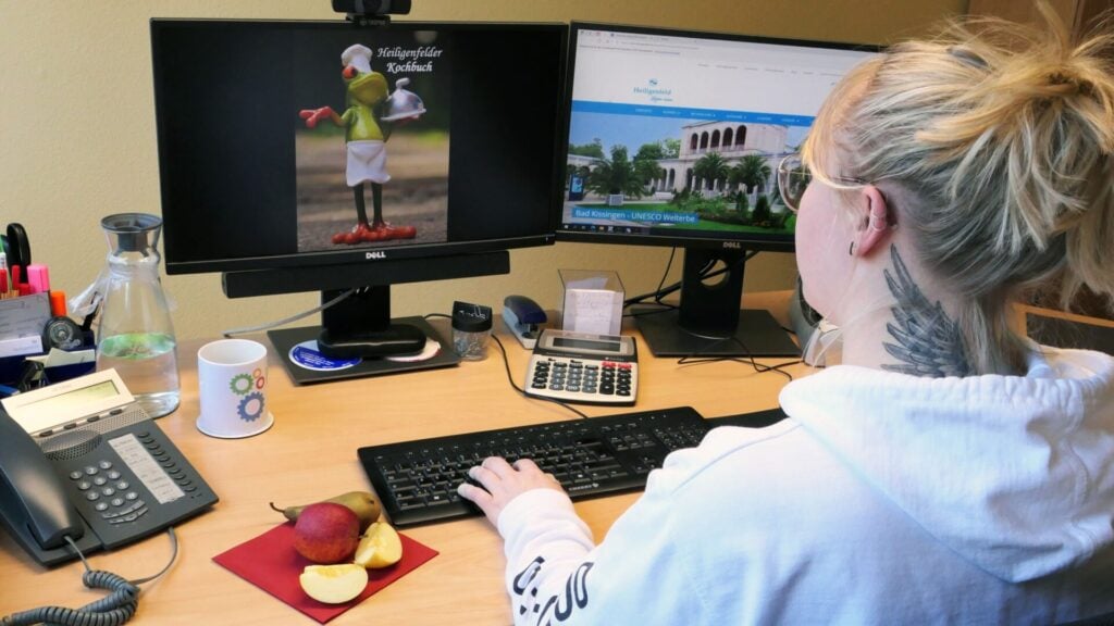 Frau arbeitet an Schreibtisch und isst einen Apfel