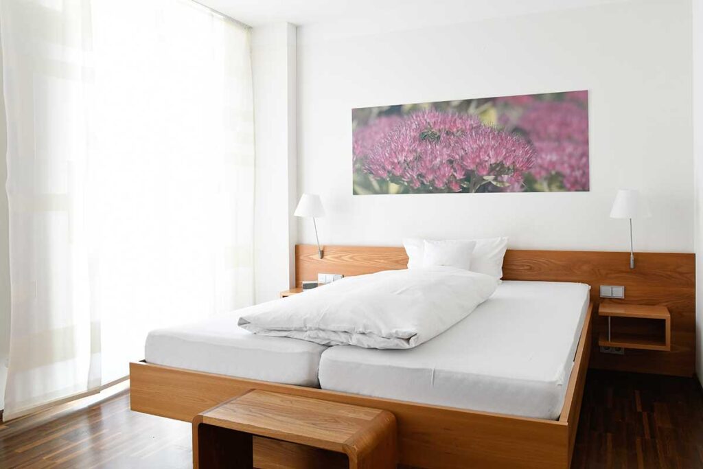 Bett unter einem Bild mit einer Lila Blume