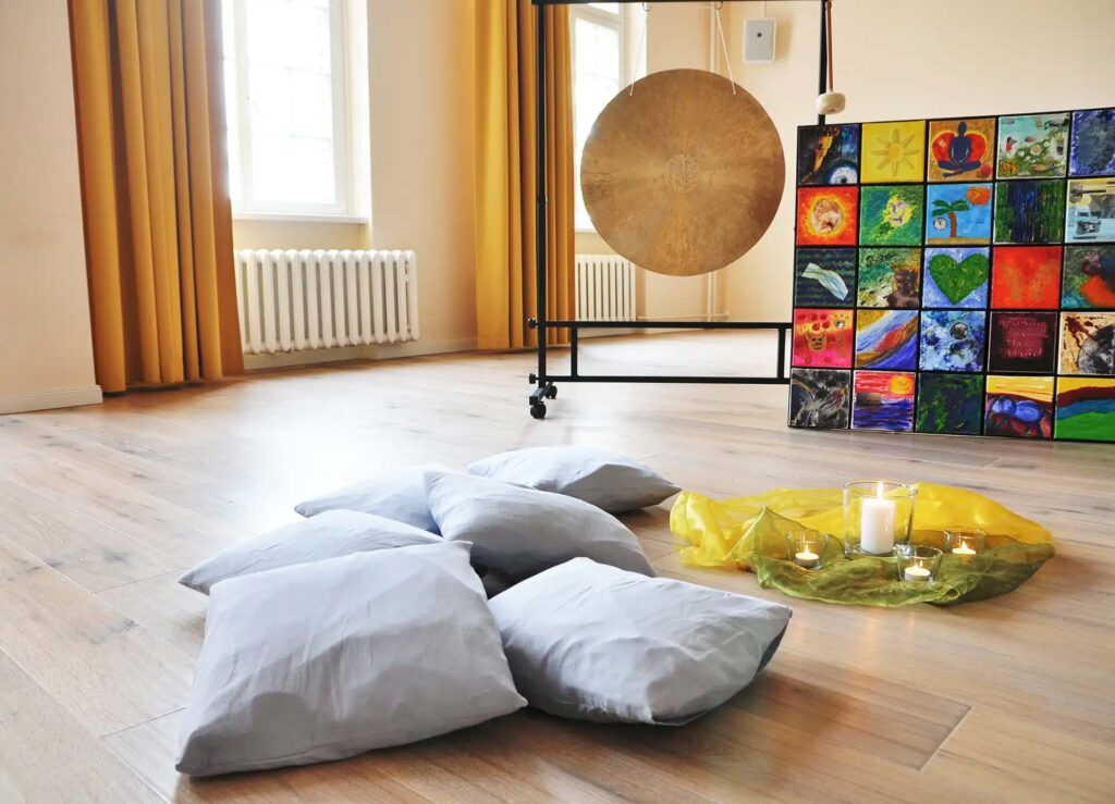 Kissen, Kerzen und Kunstwerk in einem ruhigen Meditationsraum.