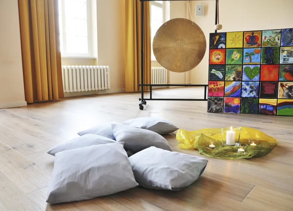 Kissen, Kerzen und Kunstwerk in einem ruhigen Meditationsraum.