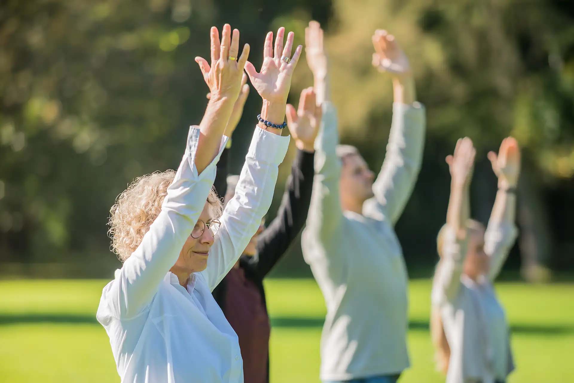Gruppe von Menschen macht Yoga-Uebungen im Freien.