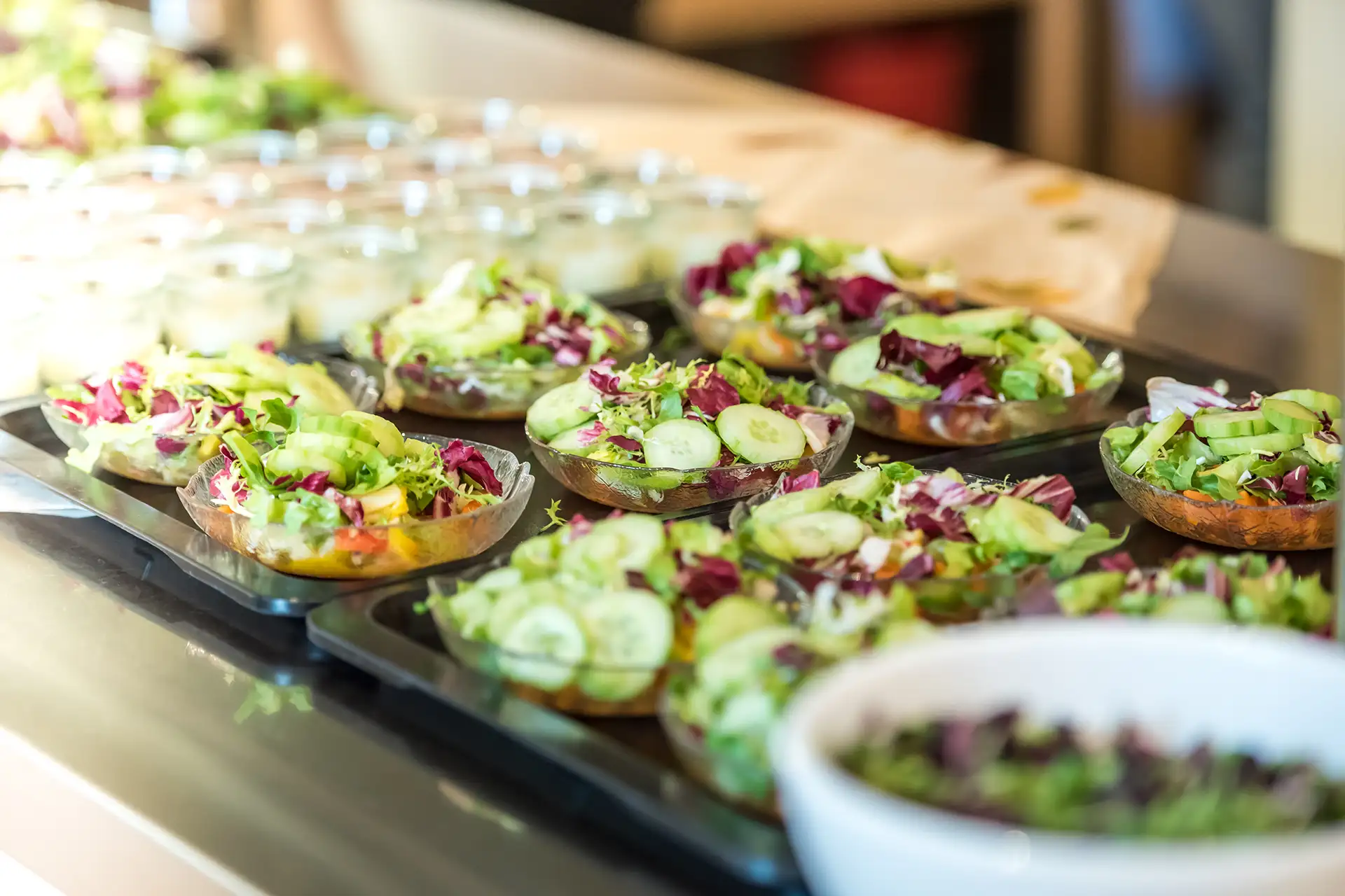 Verschiedene Salate in Schalen im Speisesaal, bereit zum Servieren.