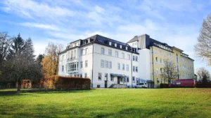 Außenansicht eines weißen und gelben Gebäudes mit grüner Wiese davor.