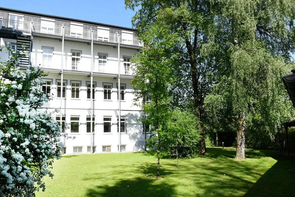 Rückansicht des Hauses mit grünem Garten und blühenden Bäumen.