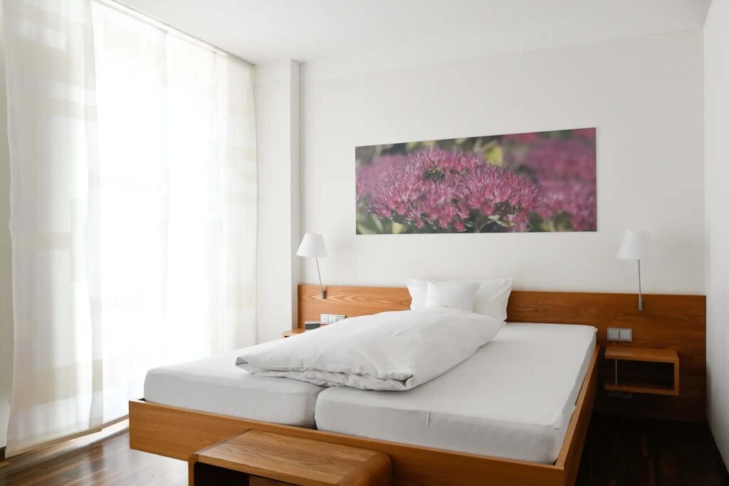 Helles Schlafzimmer mit einem großen Bett und Blumenbild an der Wand.