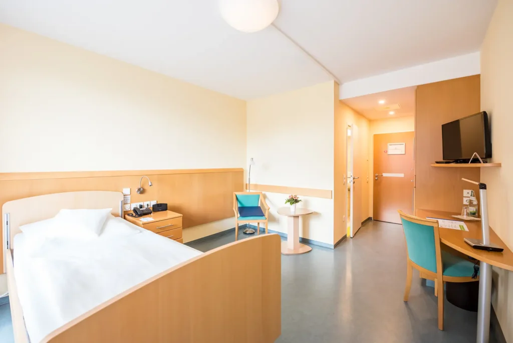 Modernes, gemütliches Einzelzimmer mit Schreibtisch und Fernseher in heller Atmosphäre.