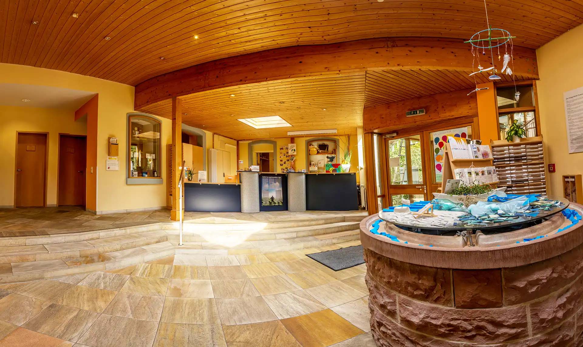 Heller Empfangsbereich mit Rezeption und Brunnen.