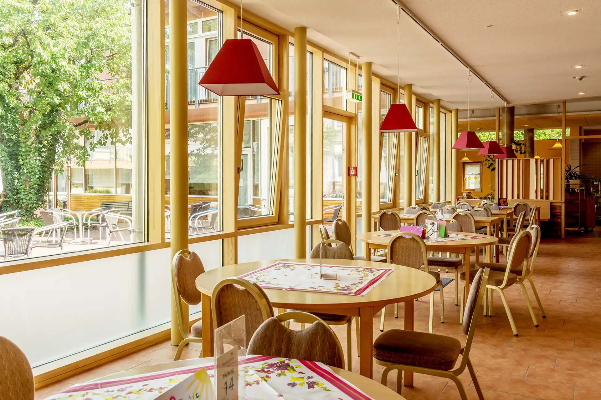 Heller Speisesaal mit großen Fenstern und Blick in den Innenhof.