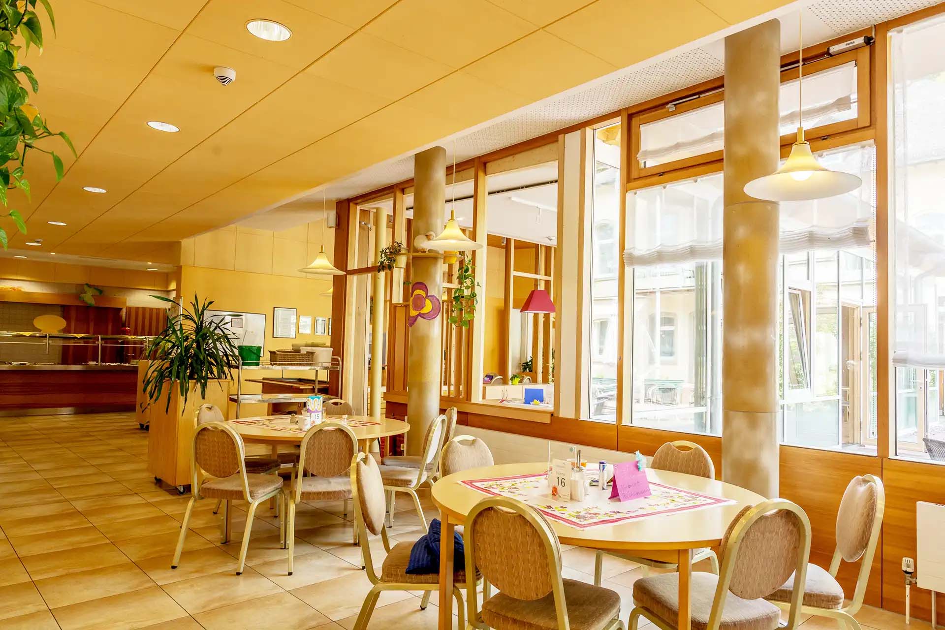 Heller Speisesaal mit großen Fenstern und gemütlichen Sitzbereichen.