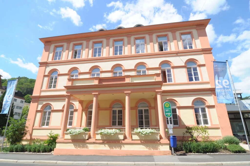 Historisches Gebaeude mit pastellfarbenen Säulen und Fenstern unter einem klaren blauen Himmel
