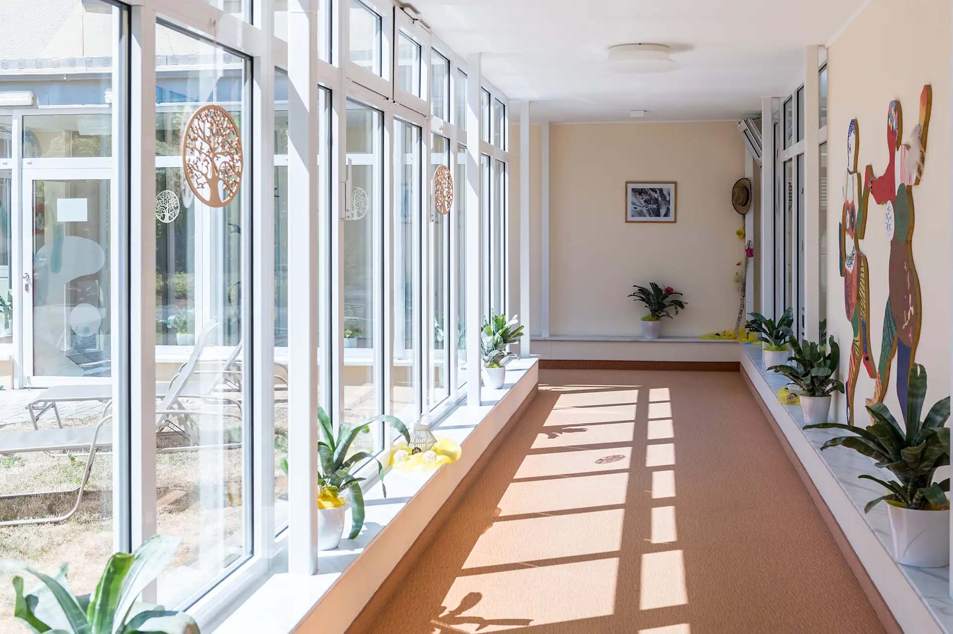 Verbindungsflur mit großen Fenstern, Dekoration und Pflanzen.