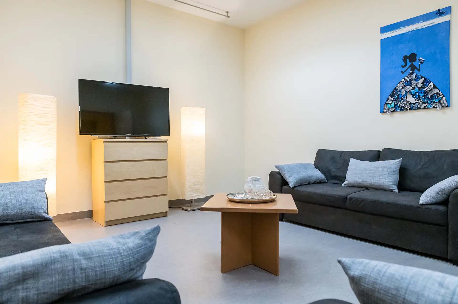 Gemuetlicher Aufenthaltsraum mit Sofas, Fernseher und dekorativem Bild an der Wand.