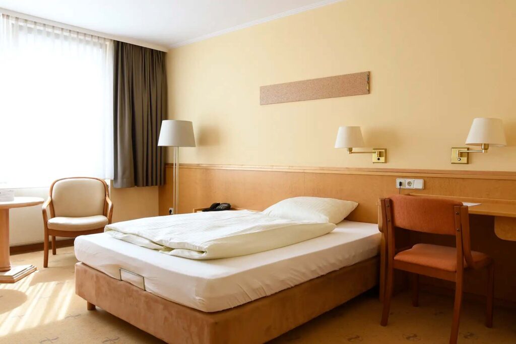 Einzelzimmer mit großem Bett, Schreibtisch und gemütlicher Sitzecke.