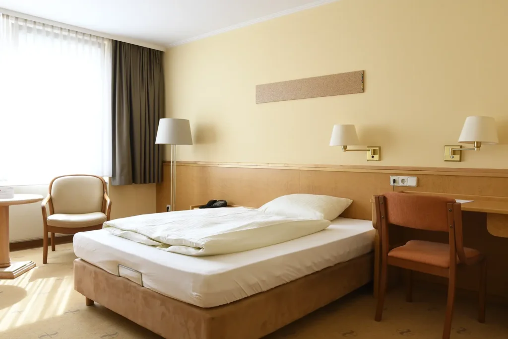 Einzelzimmer mit großem Bett, Schreibtisch und gemütlicher Sitzecke.