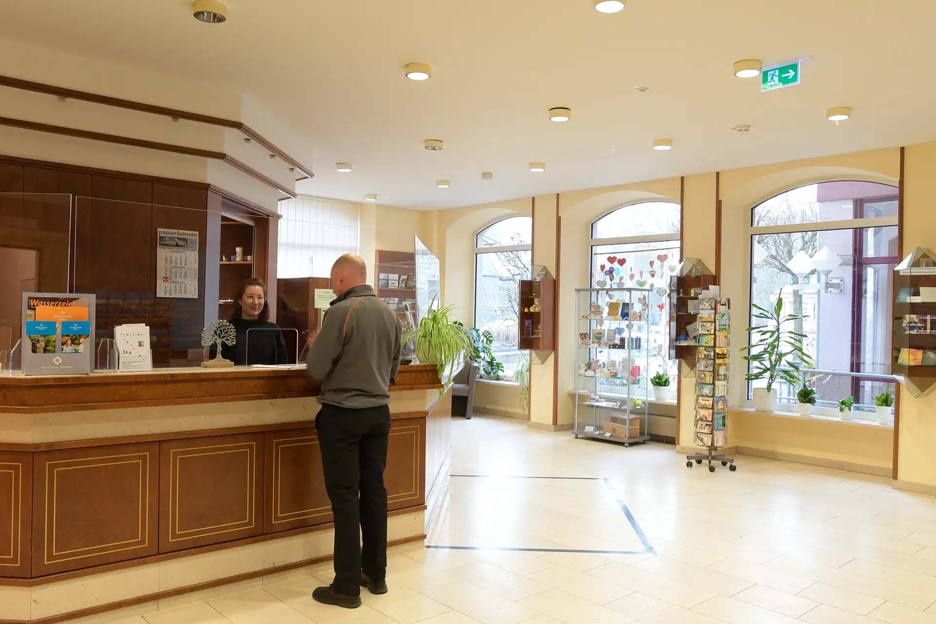 Rezeption mit einer Mitarbeiterin, die einem Gast hilft.