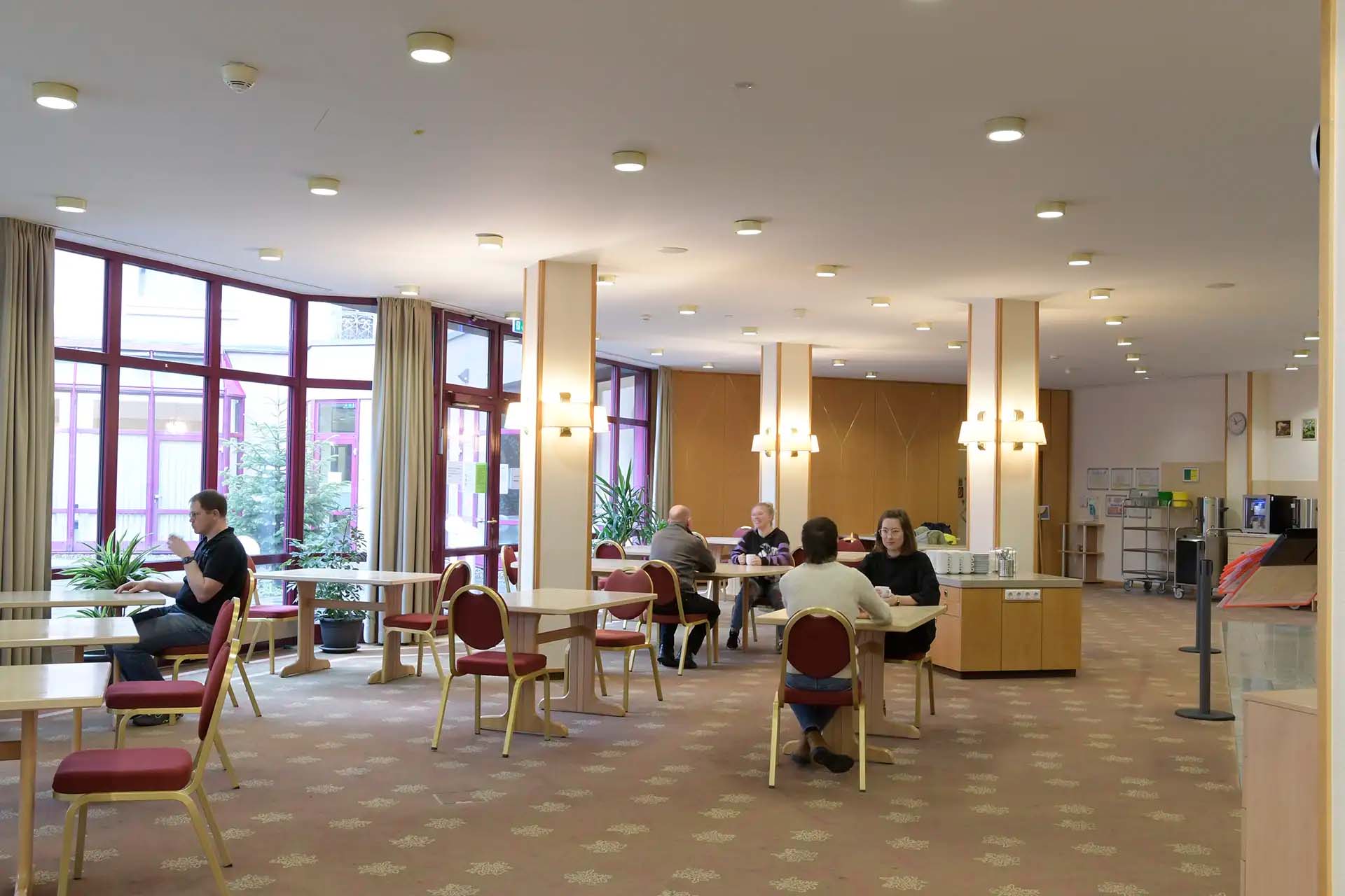 Menschen im Speisesaal, die an Tischen sitzen und sich unterhalten.