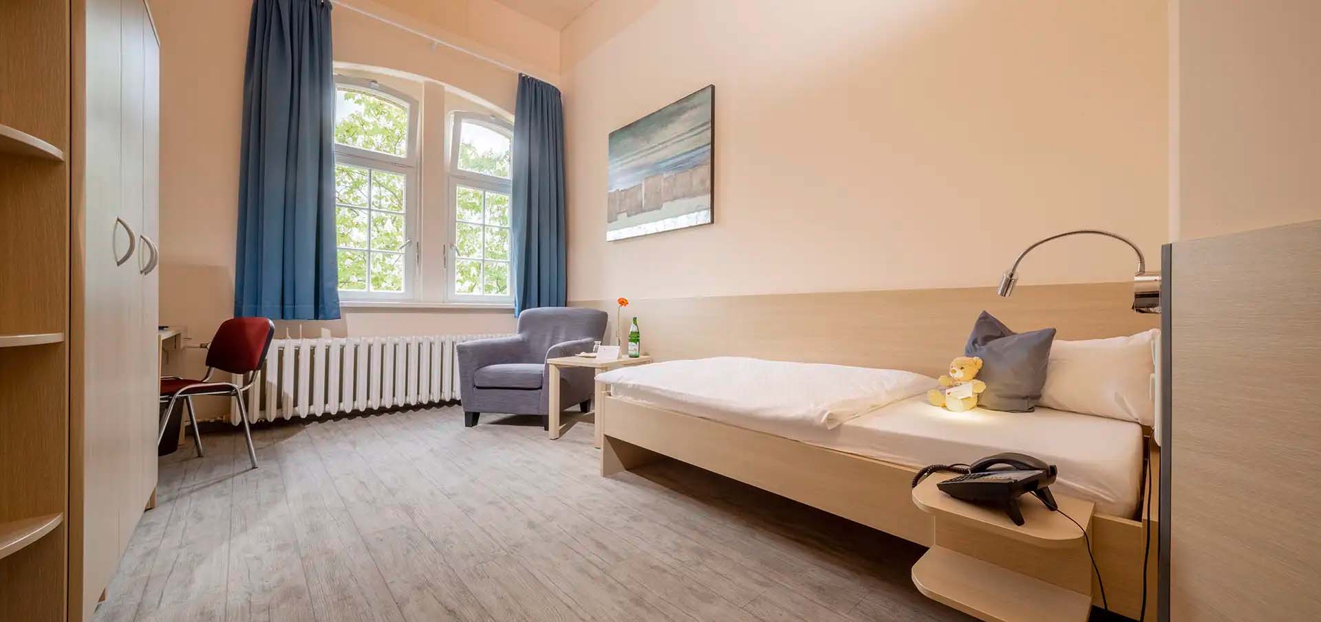 Helles Einzelzimmer mit modernem Mobiliar und großem Fenster.