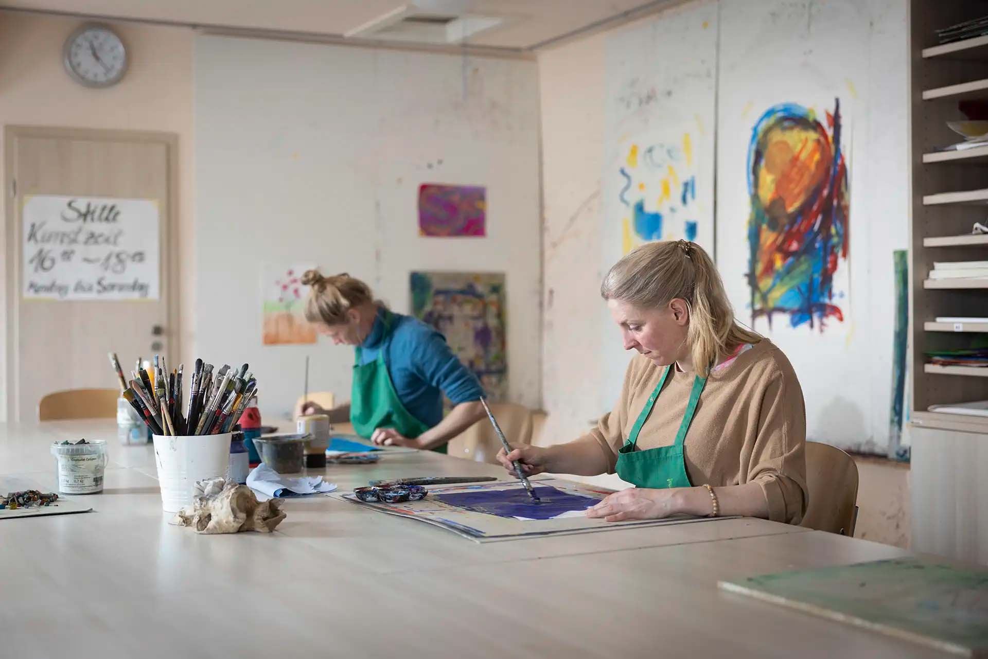 Patientinnen bei der Kunsttherapie im Malraum mit Pinsel und Farbe.