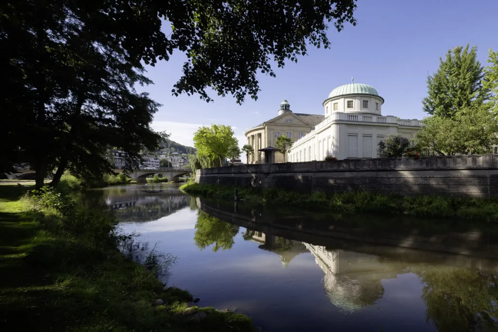 Klassizistisches Gebäude mit Kuppel, reflektiert im ruhigen Fluss.