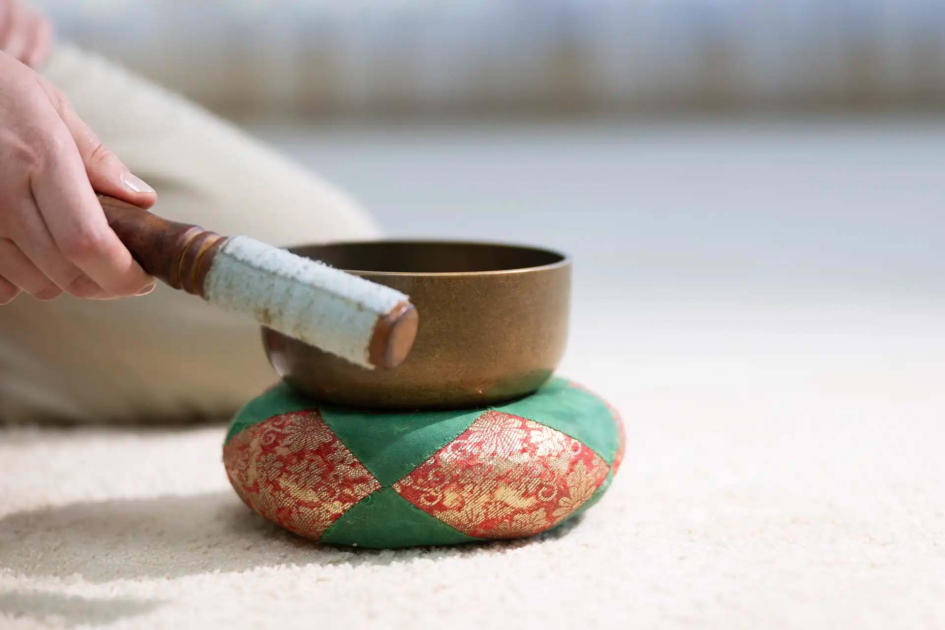 Nahaufnahme einer Klangschale auf einem dekorativen Kissen für Meditation.