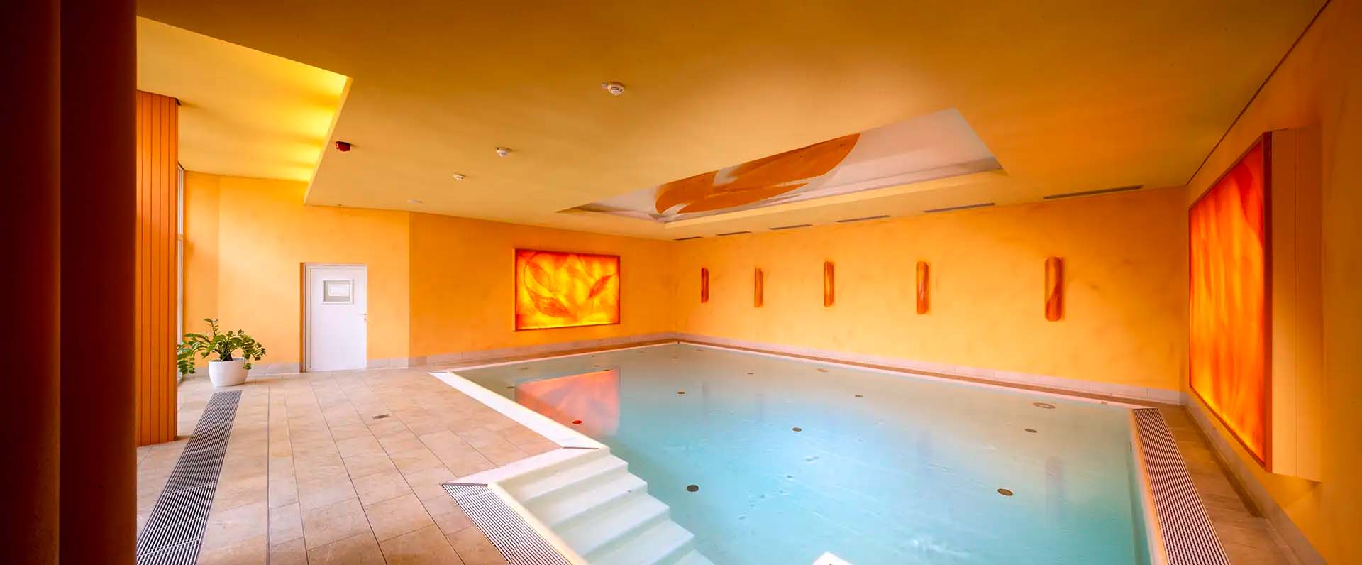 Innenpool mit warmer Beleuchtung und orangefarbenen Wänden.