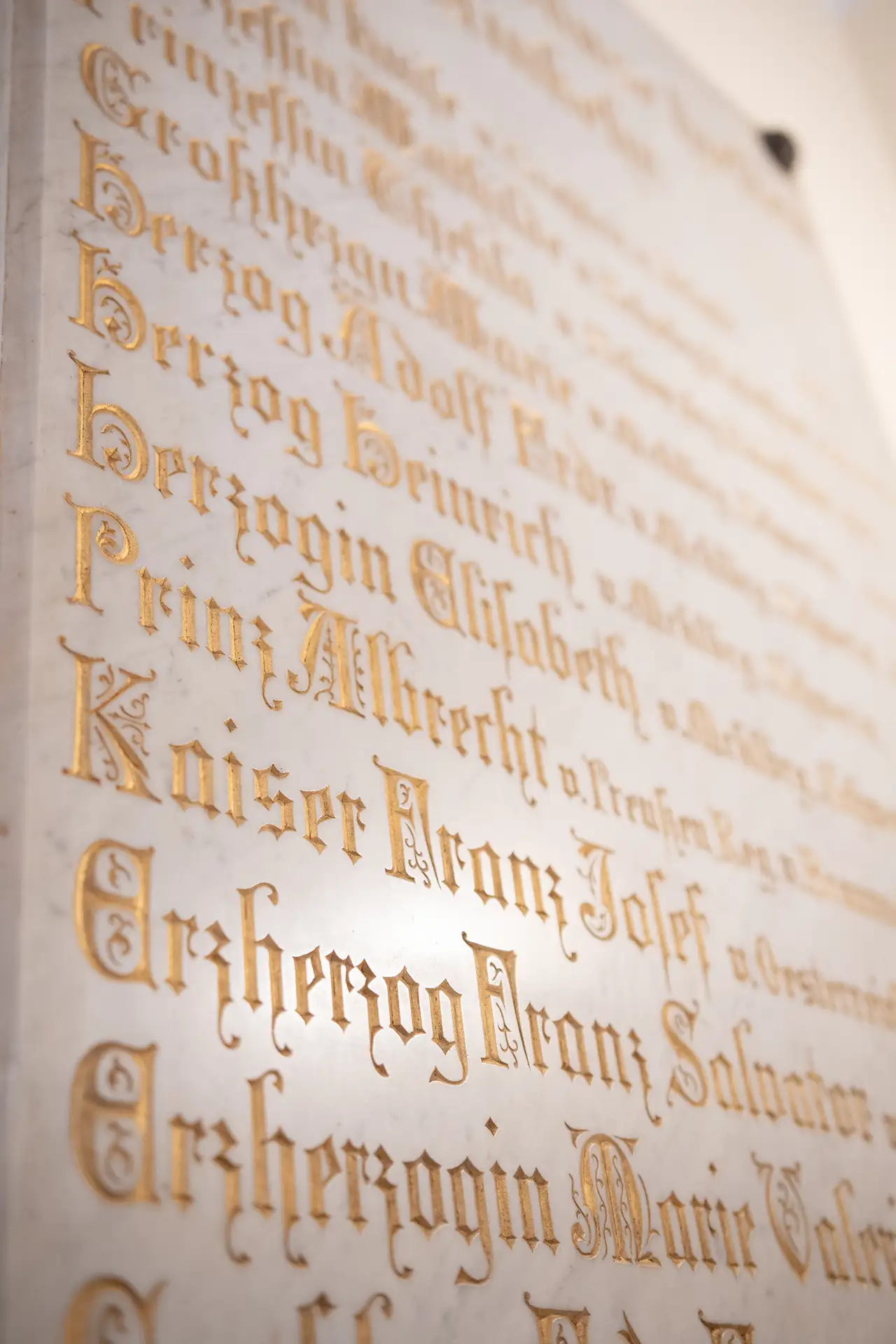 In Marmor gravierte Inschrift mit historischen Namen in goldener Schrift.