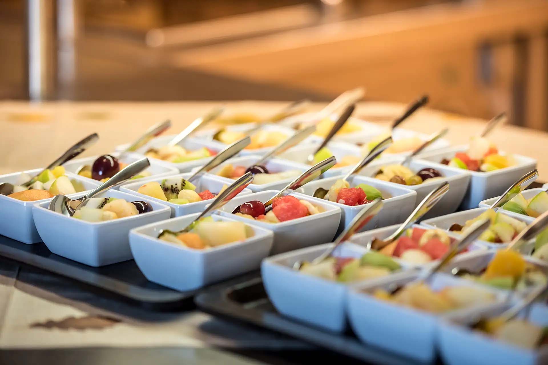 Frische Obstsalat-Schalen mit Gabeln, bereit zur Selbstbedienung am Buffet.