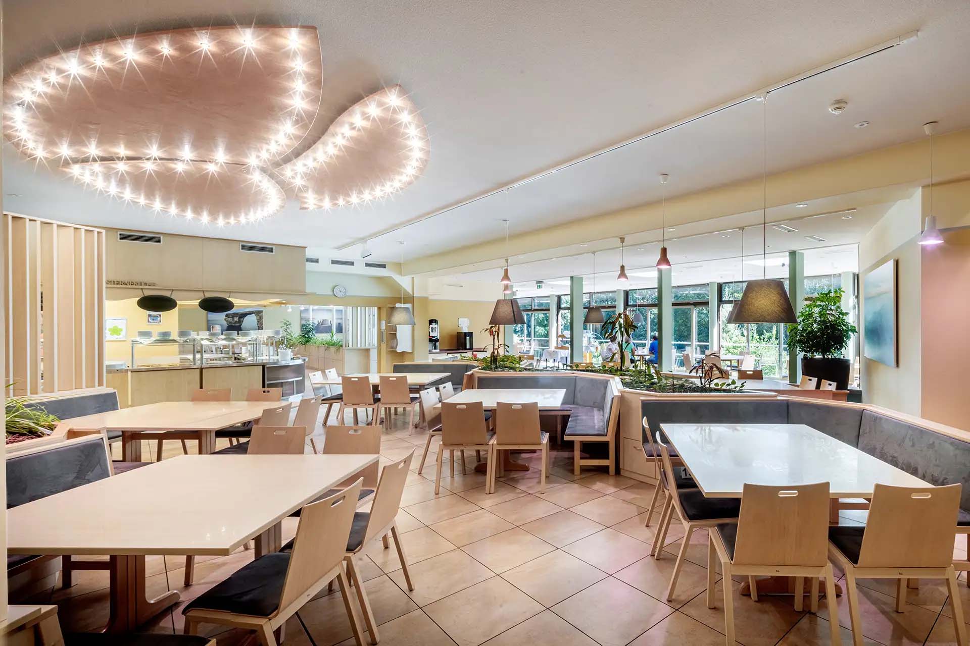 Moderner, heller Speiseraum mit stilvollen Lampen und großen Fenstern zum Garten.