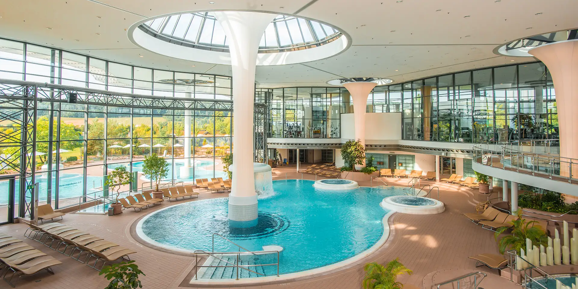 Geräumige Therme mit Indoor-Pools, Panoramafenstern und zahlreichen Liegen für Entspannung.
