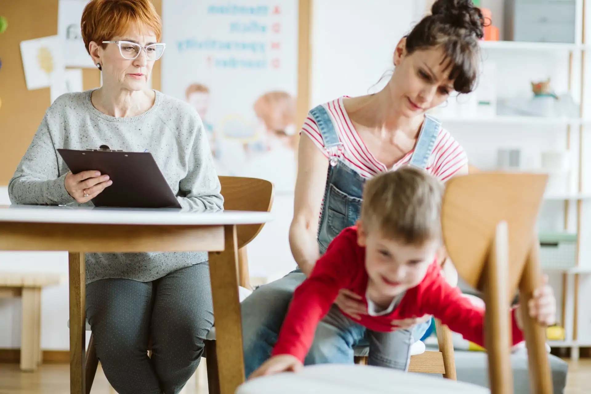 Ein unruhiges Kind in Begleitung einer Frau, beobachtet von einer Therapeutin.