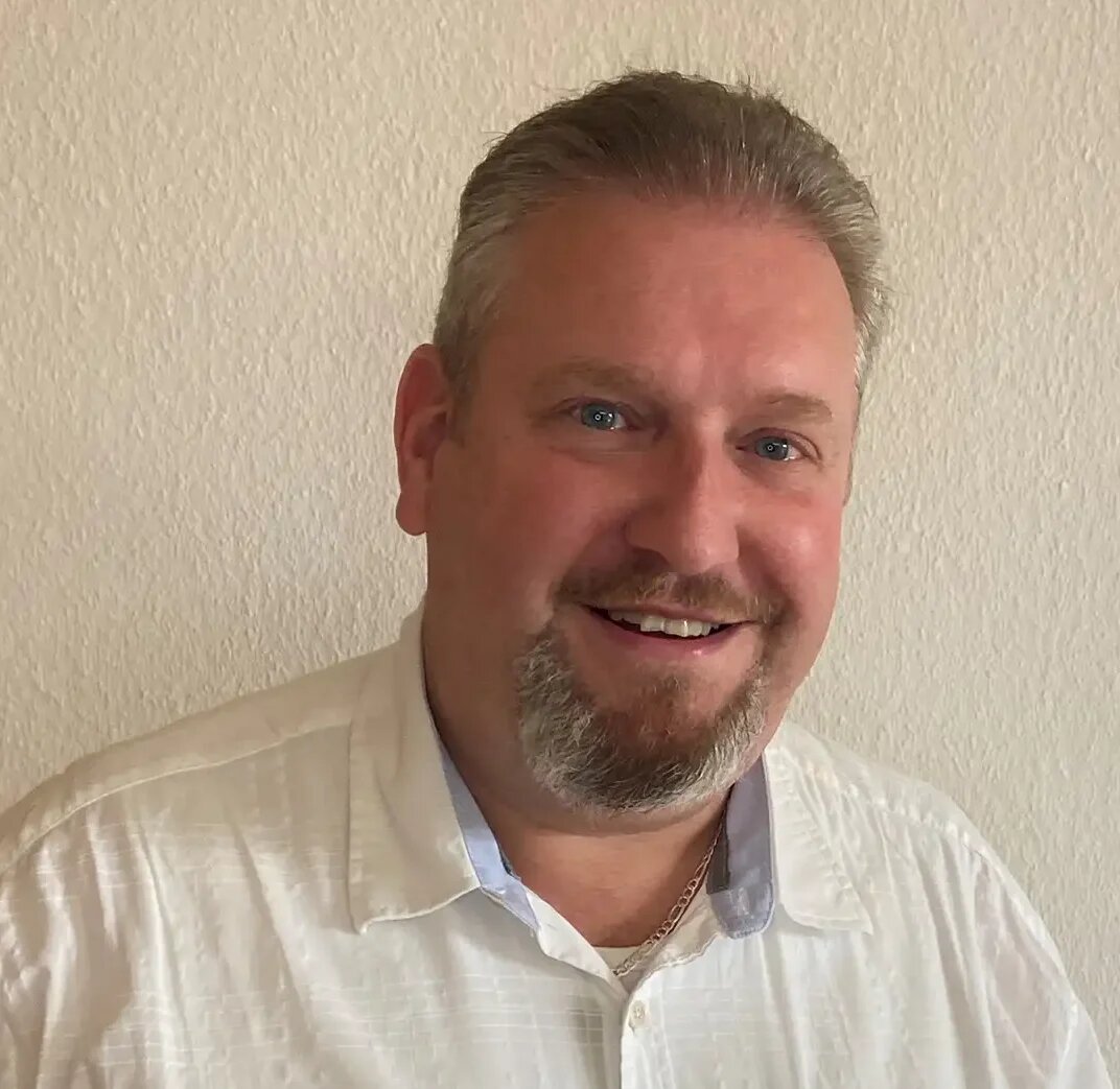 Mann mit weißem Hemd lächelt freundlich