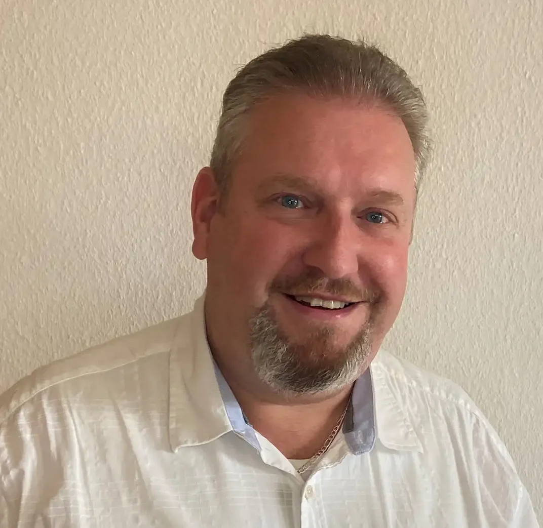 Mann mit weißem Hemd lächelt freundlich