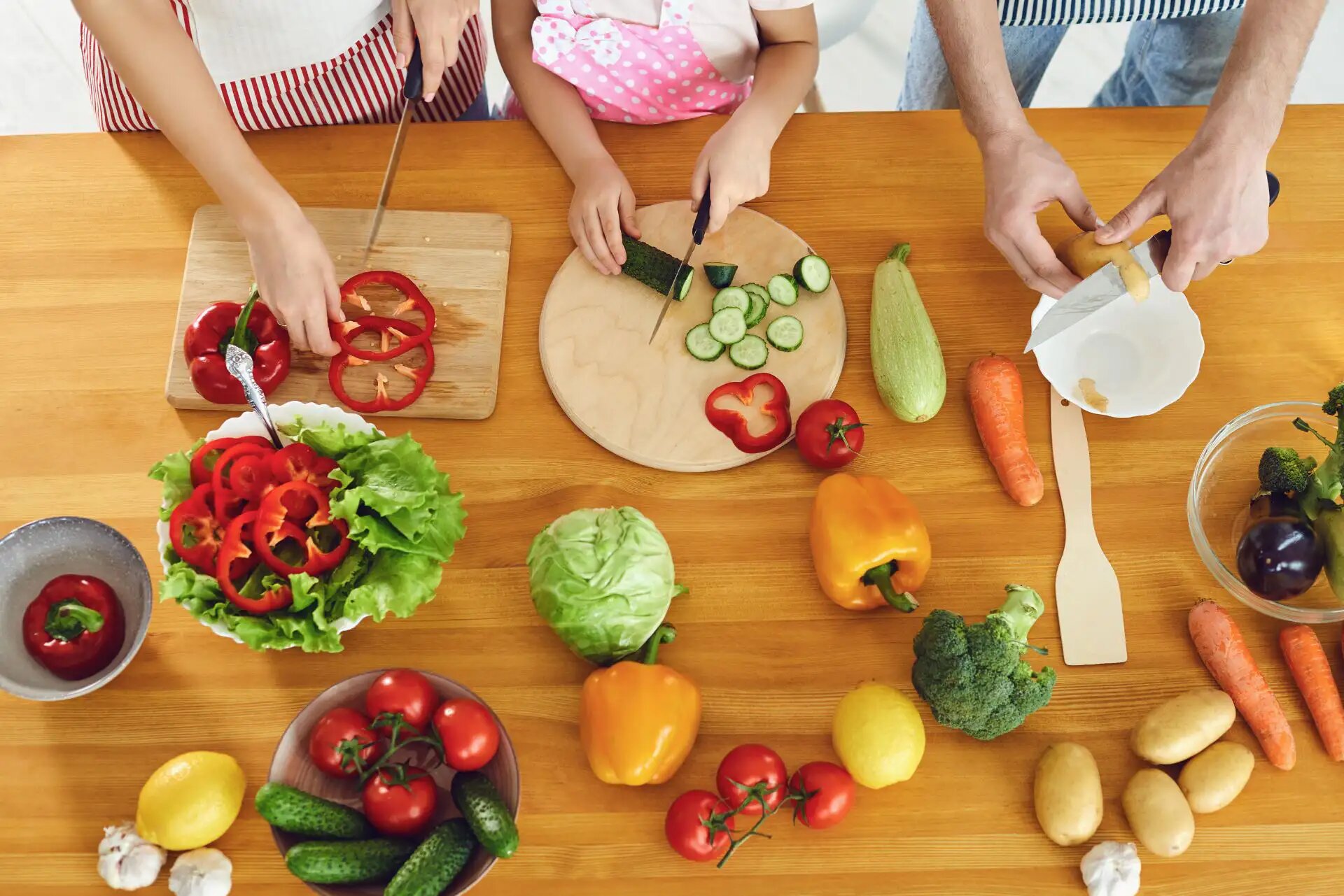 Familie schneidet frisches Gemüse für eine bunte, gesunde Mahlzeit.