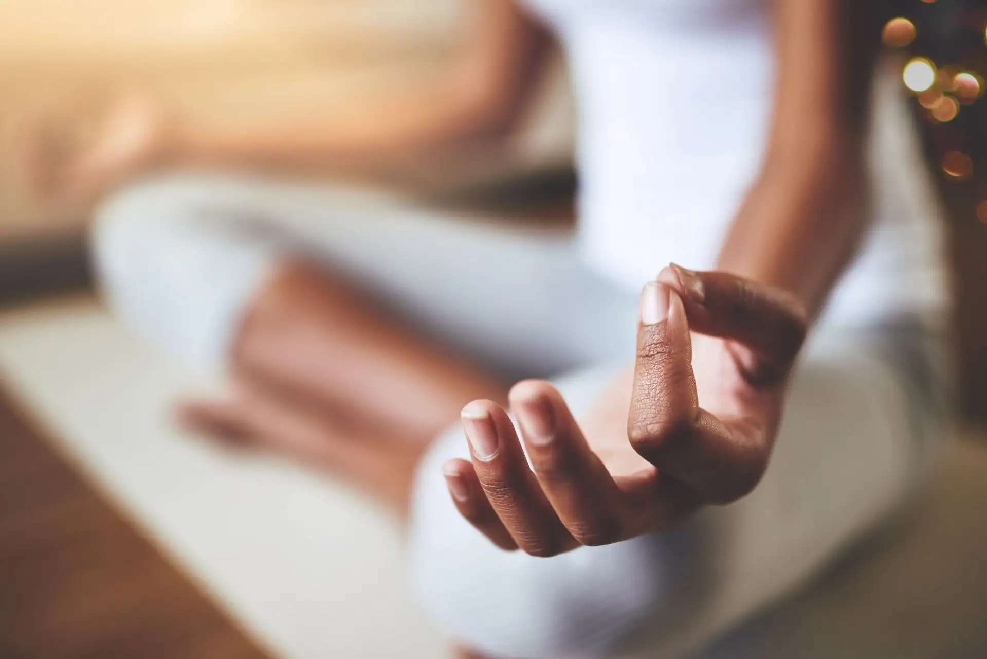 Eine Person meditiert, Hand in entspannter Mudra-Geste, strahlt Ruhe aus.