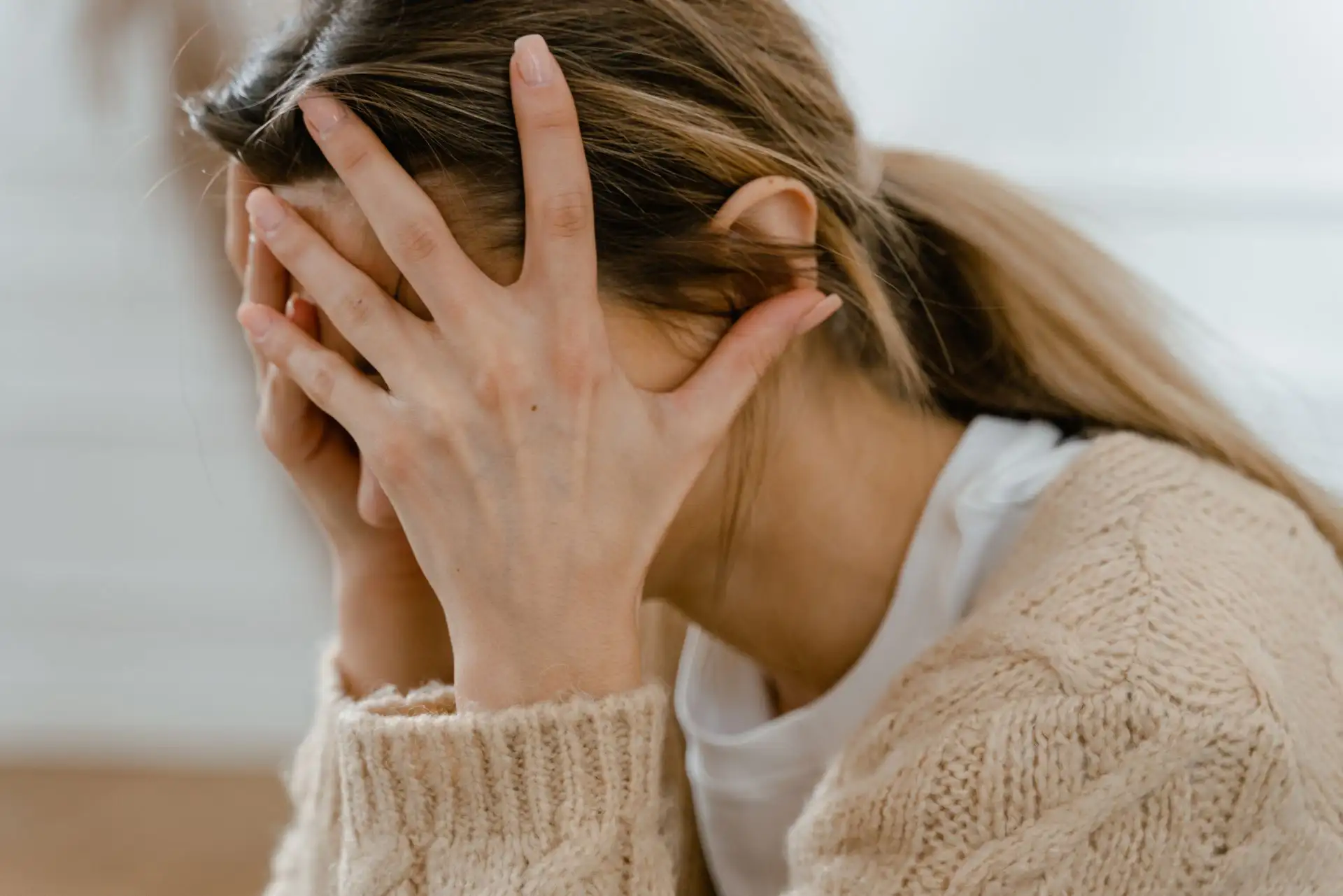 Frau hält Kopf in Händen, zeigt Stress oder Verzweiflung.