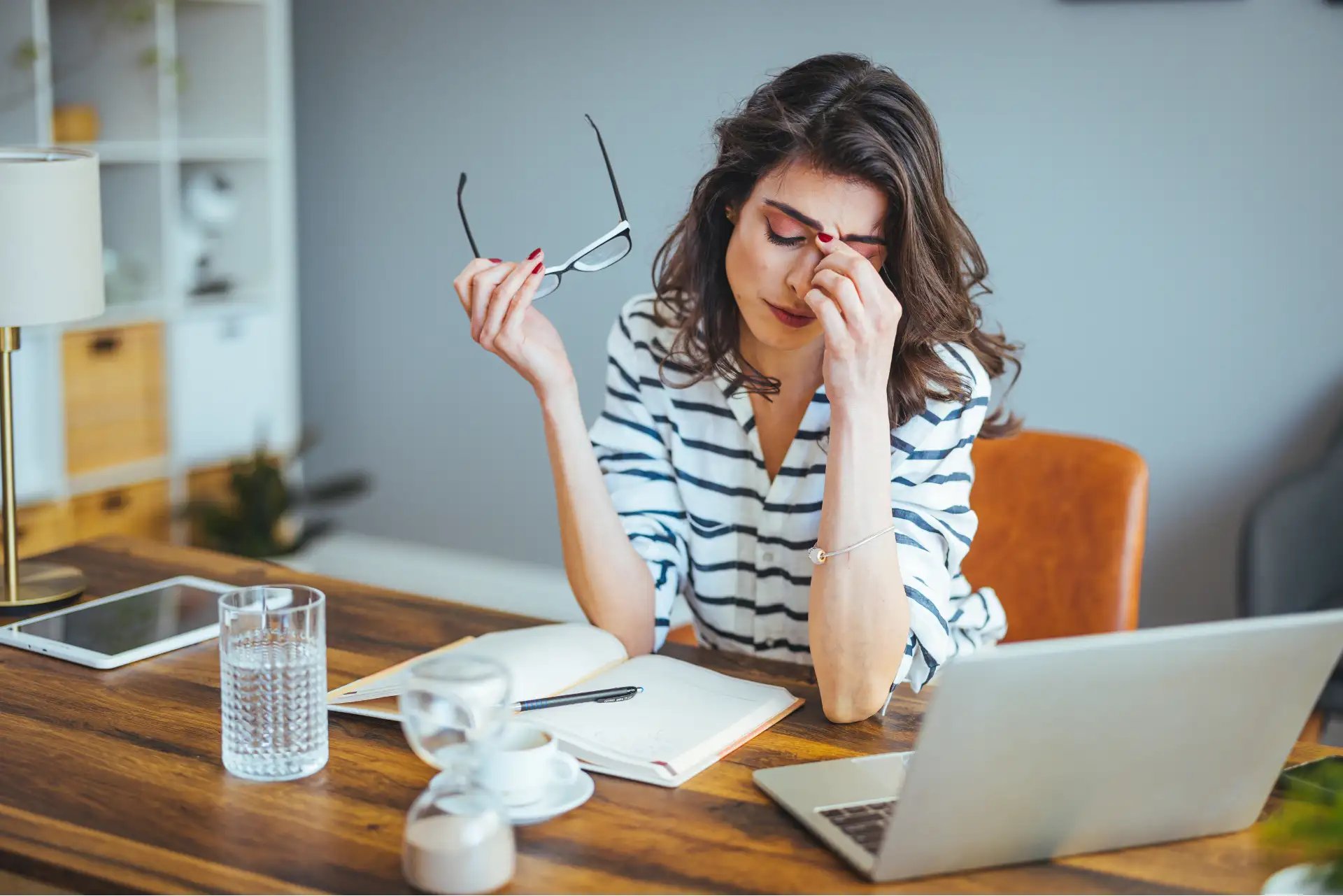 Gestresste Frau arbeitet im Homeoffice und massiert ihre Schläfen.