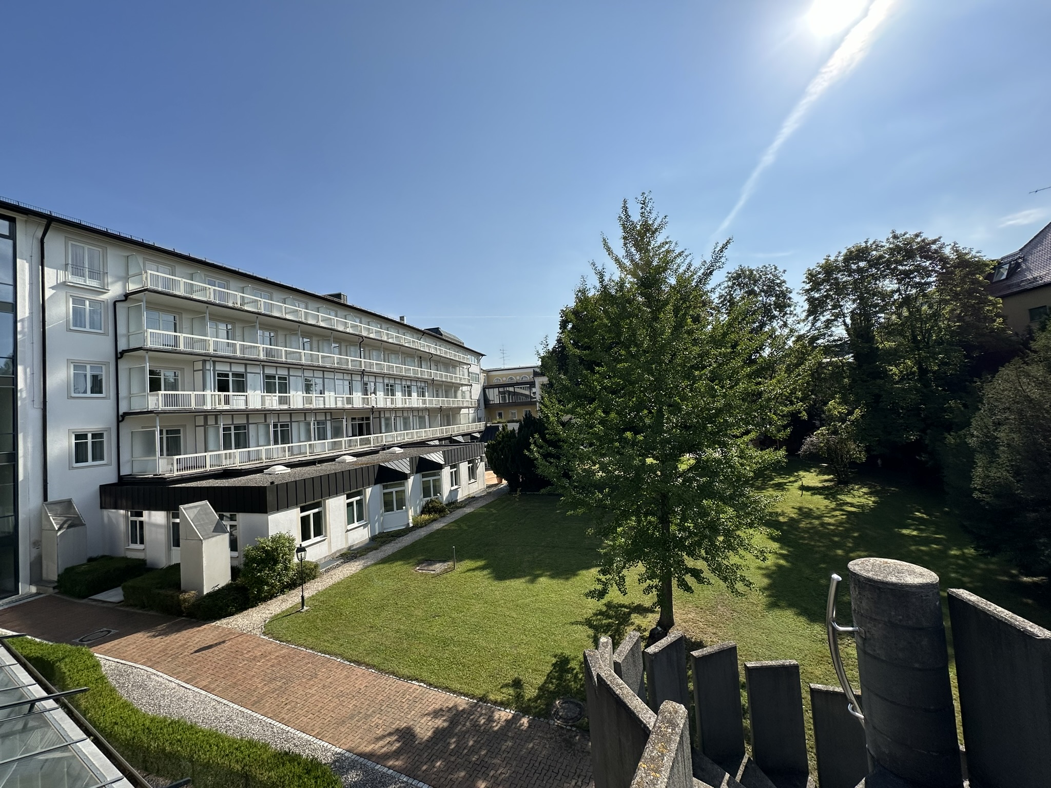 Modernes Gebäude mit Balkonen und grüner Gartenanlage bei sonnigem Wetter.